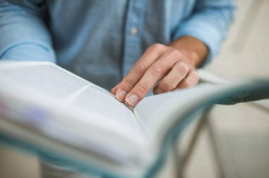 A person using their fingers to keep their place in a book.